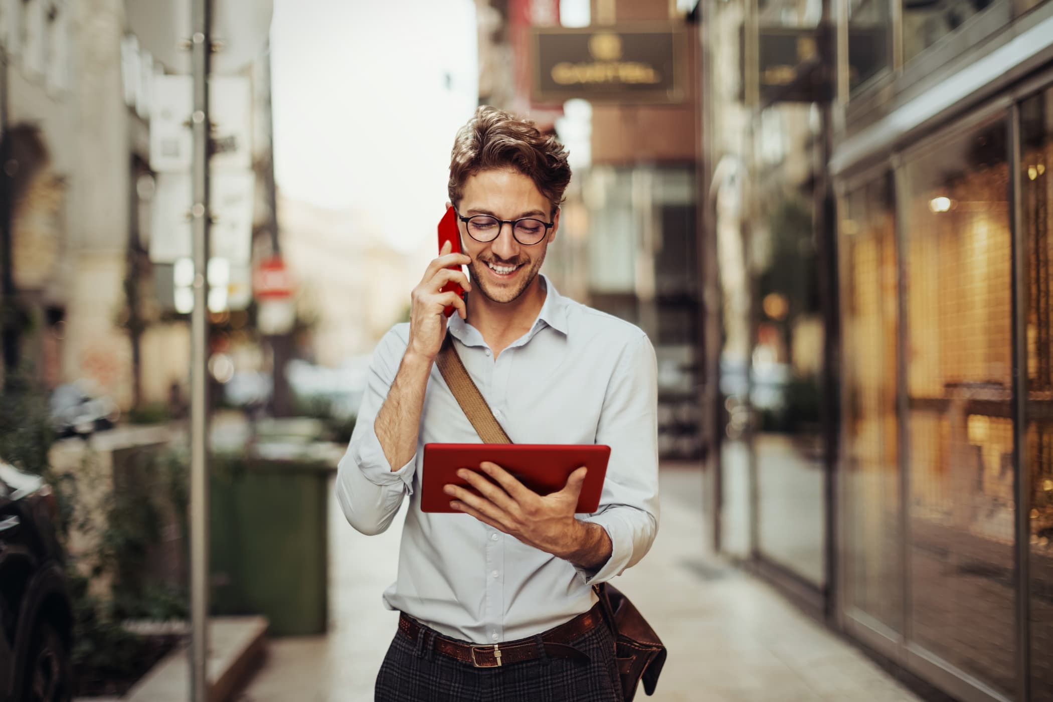 Device as a Service Busniess-Mann mit Handy am Ohr und Tablet in der Hand