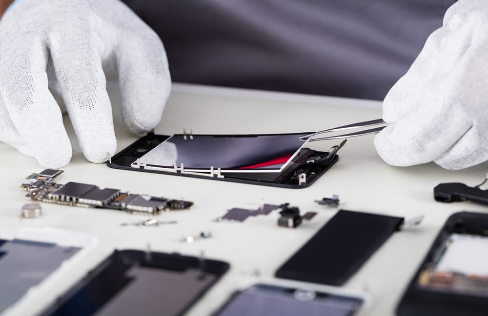 Primo piano di una persona che cambia il display di un cellulare con i guanti.