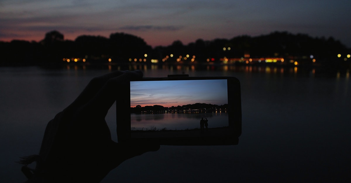 Jemand macht ein Foto von einem See in der Dämmerung